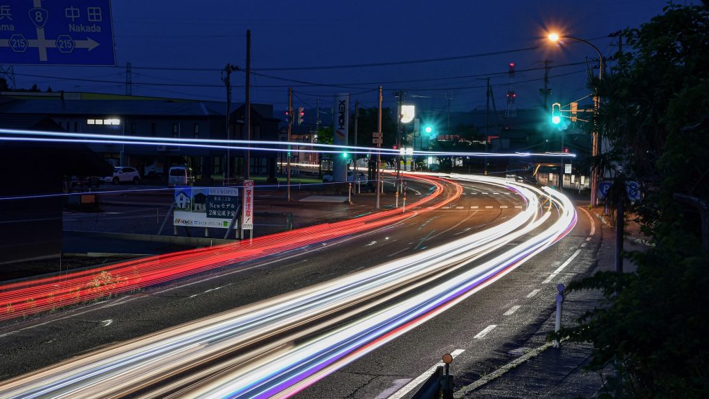 Widok na drogę nocą gdzieś w Japonii, ślady rozmytych reflektorów samochodów